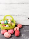 Painted Easter Eggs in decorated green basket on wooden table.