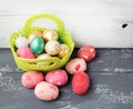 Painted Easter Eggs in decorated green basket on wooden table.