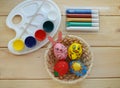 Painted Easter eggs in the form of a rabbit, a berry, a chicken and the sun in a basket  with paints Royalty Free Stock Photo