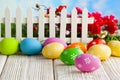 Easter eggs and white fence on wooden and grass background Royalty Free Stock Photo