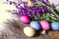 Painted Easter eggs withr the bouquet of purple wild flowers on straw mat Royalty Free Stock Photo