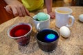 Boy paints eggs for Easter, use spoon dips eggs into colored water in the home interior