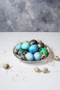 Painted eggs on plate, quail and chicken eggs, paint and brush on white wood background, Easter