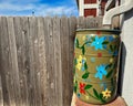 Painted Flowers on Green Rain Barrel by Wood Fence Royalty Free Stock Photo