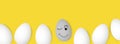 Painted gray egg between white eggs on a yellow background