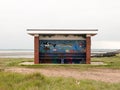 Painted public roofed seats at seaside no people