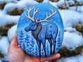 Painted round natural stones with a moose in a winter landscape Royalty Free Stock Photo