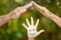 Painted smiley face on the palms against green background