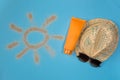 Painted sun, hat, sunscreen and sunglasses on blue background Royalty Free Stock Photo