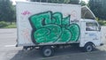 The painted truck stands at the edge of the roadway of a city street near the asphalt sidewalk.