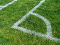 Painted white out of bounds corner on soccer pitch on green grass during daytime