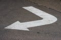 Painted white paint on the asphalt sign arrow indicating the direction of movement for cars while driving.