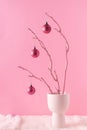 Painted wooden branch with glittering pink ornament balls in white vase on a fluffy fur and pastel pink background. Christmas