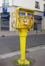 Painted yellow mailbox covered with street art by French graffiti muralist C215 in Paris
