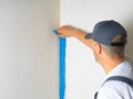 The painter applies blue paint with a brush on the wall