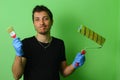Painter decorator holding a brush and roller in his hands on a background of freshly painted green wall Royalty Free Stock Photo