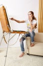 Painter female with wooden sketchbook sitting on sofa and painting