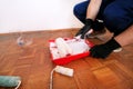 Painter with gloves holds white roller brush in his hand and mixes paint in container and red bowl for color mixing. Royalty Free Stock Photo