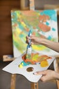 Painter holding palette and paintbrush, mixing acrylic paints colors Royalty Free Stock Photo