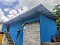 A painter on ladder ,paints the shutter door of newly constructed factory shed