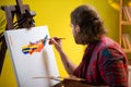 A painter is looking directly into the camera and smiling as he is holding up his art palette and sitting in a chair in Royalty Free Stock Photo