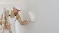 Painter man decorator work of home to renovate, painting with roller paint on wall, with wooden ladder,  on white, copy Royalty Free Stock Photo