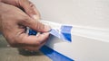 Painter Man Removing masking blue tape from molding, baseboard