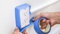 Painter Man Using Masking Blue Tape to Secure Electric Outlet Royalty Free Stock Photo