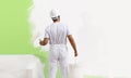 Painter man at work with a paint roller, wall painting green col Royalty Free Stock Photo