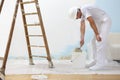 Painter man at work takes the color with paint brush from the bu Royalty Free Stock Photo
