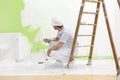 Painter man at work takes the color with paint roller from the b Royalty Free Stock Photo