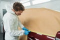 Painter masking car with paper and tape before painting in auto repair service booth. Royalty Free Stock Photo