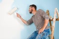 Painter in paint splattered shirt painting a wall Royalty Free Stock Photo