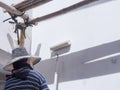 A painter is painting the exterior under the eaves of a gray concrete roof