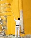 Painter painting the facade of a ancient buildind with roller, Spain