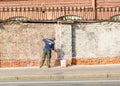 Painter paints a brick fence around the building