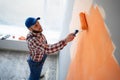 Painter paints a wall orange with a paint roller, top view Royalty Free Stock Photo