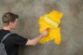 Painter repaints a structured wall in yellow with a color roller Royalty Free Stock Photo