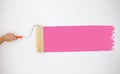 Painter`s hand held roller to painting pink color paints on the grey wall. Royalty Free Stock Photo