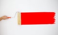 Painter`s hand held roller to painting red color paints on the grey wall. Royalty Free Stock Photo