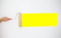 Painter`s hand held roller to painting yellow color paints on the grey wall. Royalty Free Stock Photo