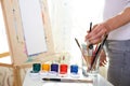Painter`s hand holds brush on the background of easel Royalty Free Stock Photo