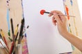 Painter`s hand holds brush on the background of easel Royalty Free Stock Photo