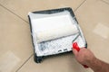 A painter's hand lowers a roller into a plastic tray with white paint Royalty Free Stock Photo