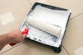 A painter's hand lowers a roller into a plastic tray with white paint Royalty Free Stock Photo