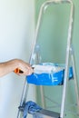 Painter`s ladder and hand wringing paint roller. Interior of the house. Vertical photo