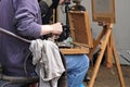 Painter sits near easel with open box of paint colors Royalty Free Stock Photo