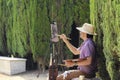 Painter is sitting in Barcelona ciudadela park among green plants