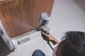 A painter sprays lacquer wood finish to the end panel of the bottom cabinet in the kitchen.