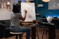 Painter student standing in front of canvas drawing artistic vase